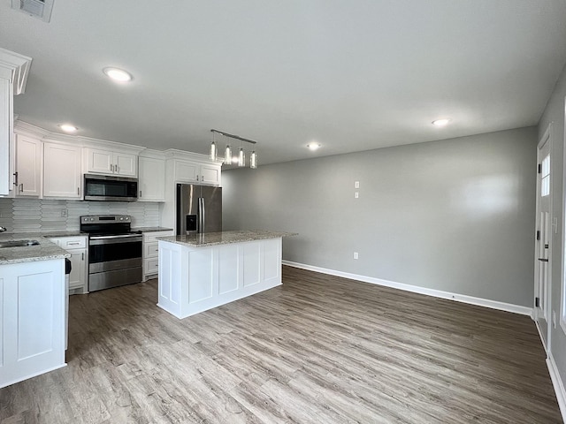 402 Pine St, Pulaski, TN 38478 - kitchen with appliances with stainless steel finishes, baseboards, a kitchen island, wood finished floors, and recessed lighting