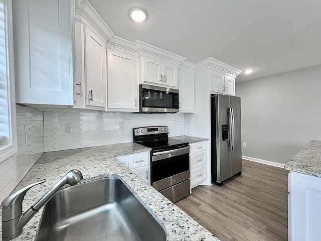 402 Pine St, Pulaski, TN 38478 - kitchen with stainless steel appliances, a sink, white cabinets, wood finished floors, and baseboards