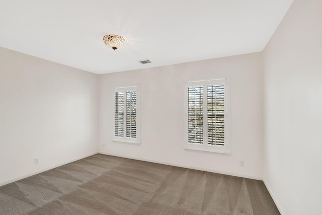 carpeted spare room with plenty of natural light, baseboards, and visible vents
