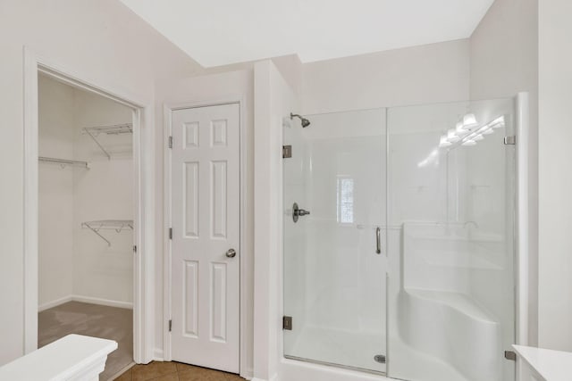 full bath featuring a spacious closet, tile patterned floors, and a shower stall
