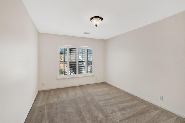 spare room featuring baseboards, visible vents, and carpet flooring
