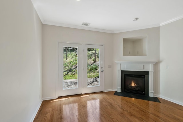 unfurnished living room with a fireplace with flush hearth, visible vents, crown molding, baseboards, and hardwood / wood-style floors