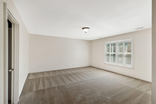 empty room with baseboards, visible vents, and carpet floors
