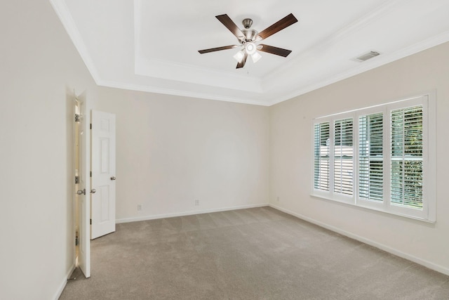 unfurnished room with a tray ceiling, ornamental molding, a ceiling fan, and light colored carpet