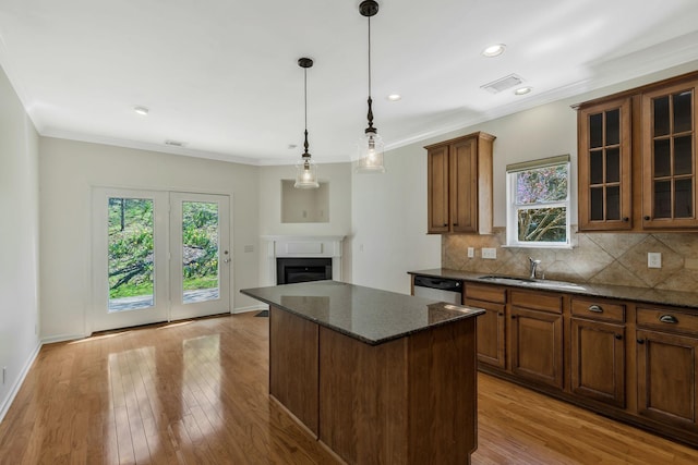 kitchen featuring backsplash, a sink, dishwashing machine, brown cabinetry, and ornamental molding