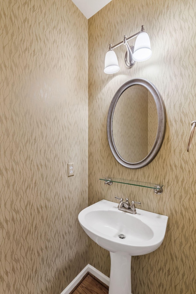 bathroom with baseboards, wallpapered walls, and wood finished floors