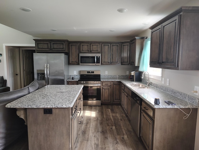 kitchen with dark wood-style flooring, light stone countertops, a sink, and stainless steel appliances