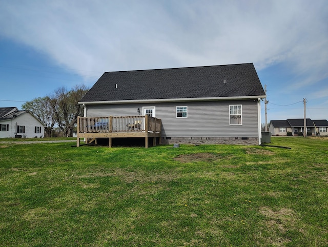 rear view of house featuring crawl space, roof with shingles, a deck, and a lawn