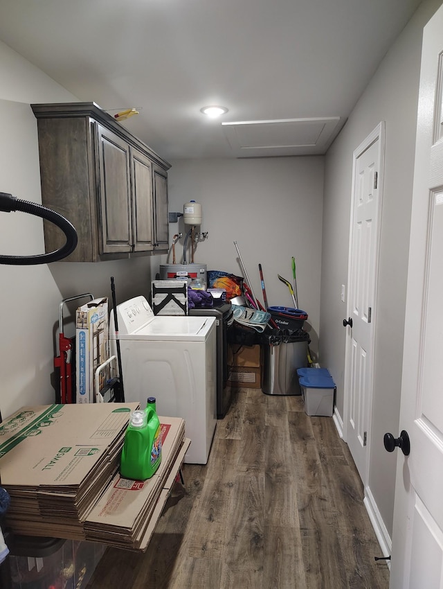 clothes washing area featuring dark wood-style floors, cabinet space, washing machine and dryer, and baseboards