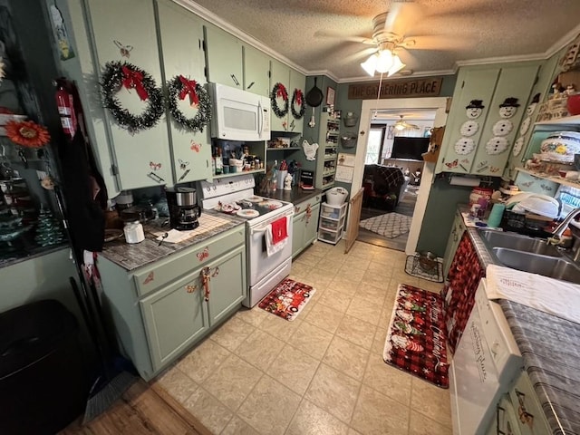 kitchen with green cabinets, white appliances, ornamental molding, a sink, and a ceiling fan