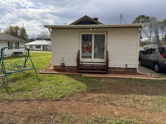rear view of house with a lawn and entry steps