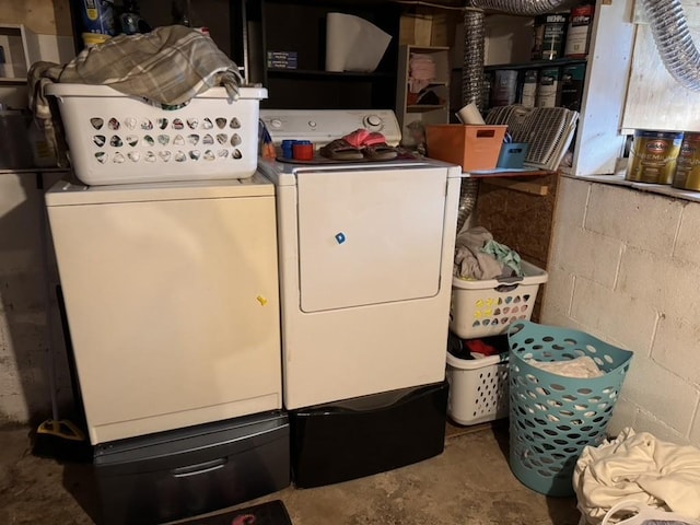 washroom featuring washing machine and clothes dryer, concrete block wall, and laundry area