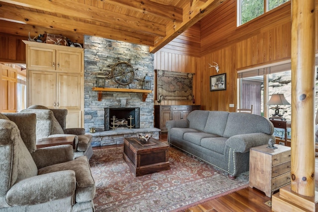living area featuring wooden ceiling, a stone fireplace, beam ceiling, wood finished floors, and wood walls