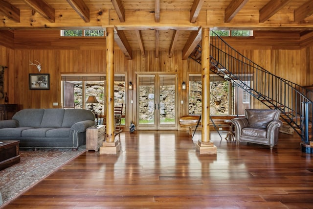 living area featuring plenty of natural light, wooden walls, french doors, and beam ceiling