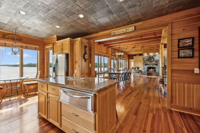 kitchen featuring stainless steel refrigerator with ice dispenser, a chandelier, a warming drawer, a healthy amount of sunlight, and a center island