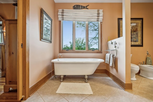 bathroom featuring tile patterned floors, baseboards, and a freestanding tub