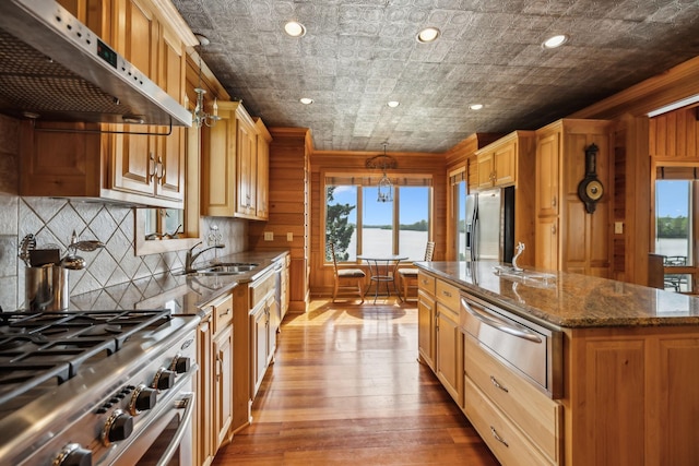 kitchen featuring a warming drawer, a wealth of natural light, under cabinet range hood, stainless steel appliances, and a sink