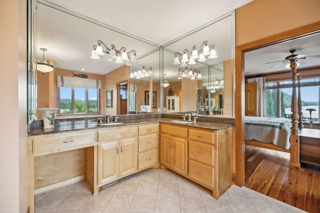full bath featuring double vanity, tile patterned floors, connected bathroom, ceiling fan with notable chandelier, and a sink