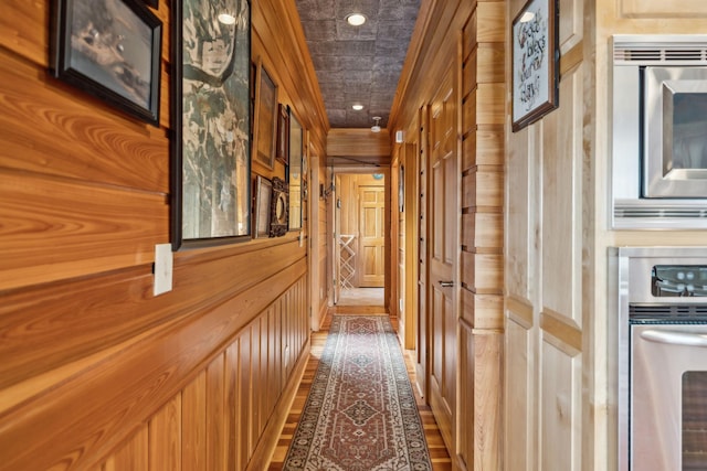 corridor featuring wooden walls and recessed lighting