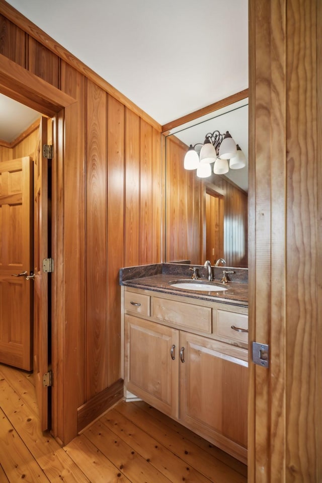 bathroom with wood walls, wood-type flooring, and vanity
