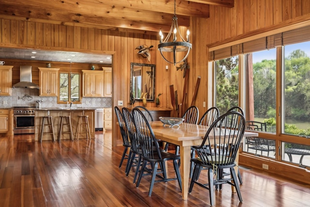 dining space featuring wooden walls, beamed ceiling, and dark wood finished floors