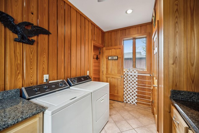 laundry room with wooden walls, washing machine and dryer, cabinet space, and light tile patterned flooring