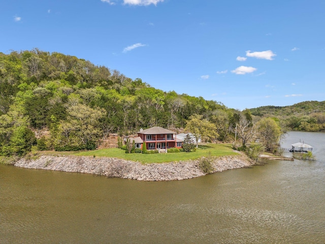 birds eye view of property featuring a water view and a wooded view
