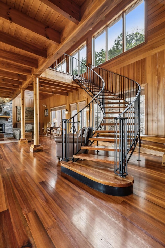 stairway with wooden walls, beamed ceiling, wooden ceiling, and wood finished floors