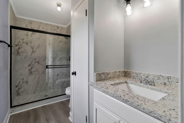 bathroom featuring crown molding, toilet, vanity, a marble finish shower, and wood finished floors