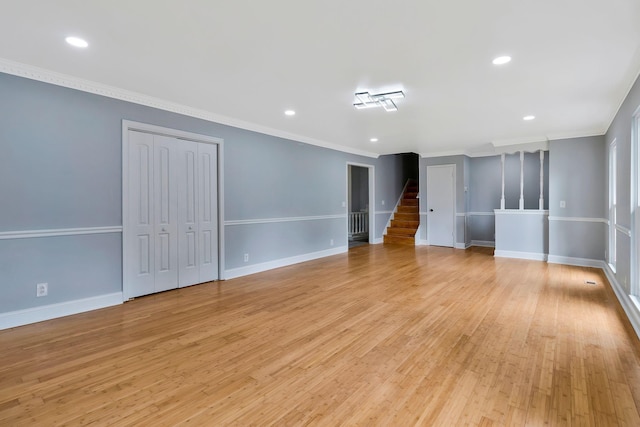 spare room with baseboards, ornamental molding, stairway, and light wood finished floors