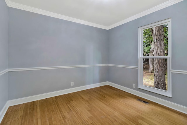 spare room with visible vents, crown molding, baseboards, and wood finished floors
