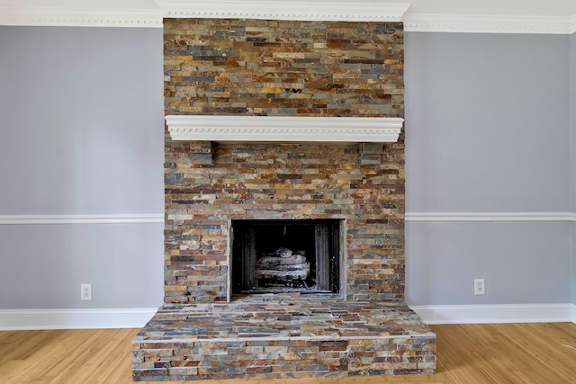 details with baseboards, ornamental molding, wood finished floors, and a fireplace with raised hearth