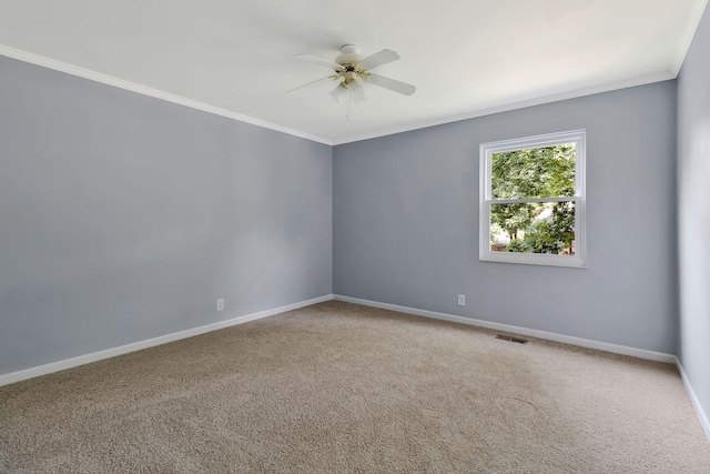spare room with carpet flooring, visible vents, baseboards, ornamental molding, and a ceiling fan