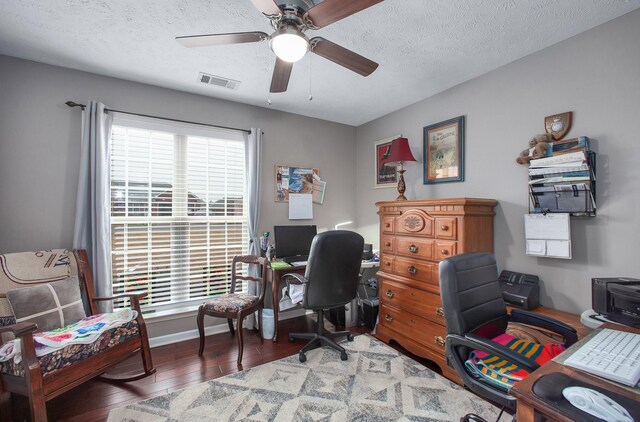home office with a textured ceiling, visible vents, baseboards, ceiling fan, and hardwood / wood-style floors