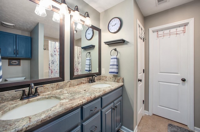 full bathroom with tile patterned floors, double vanity, a sink, and baseboards