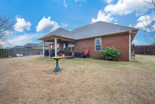 back of property with roof with shingles, brick siding, a patio area, and a lawn