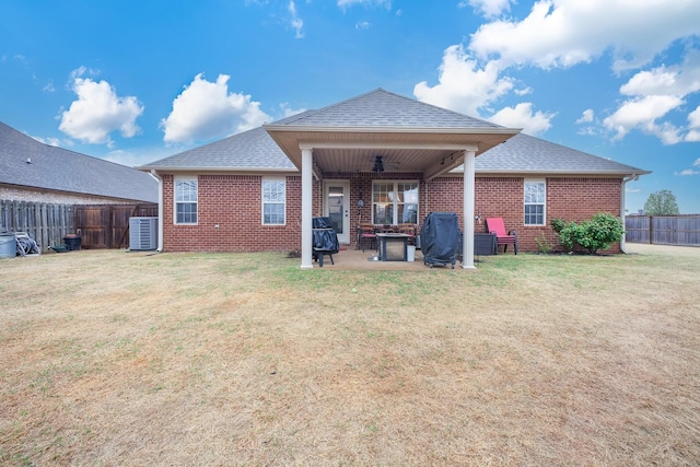 rear view of house featuring a fenced backyard, a yard, brick siding, and roof with shingles