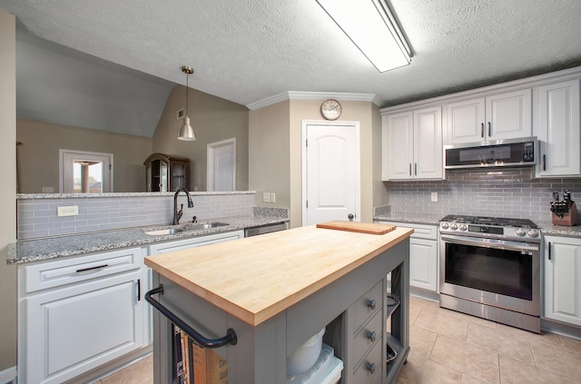 kitchen with a sink, butcher block counters, a kitchen island, and appliances with stainless steel finishes