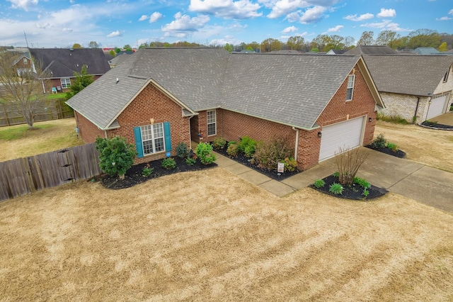 ranch-style home with driveway, fence, brick siding, a front lawn, and a shingled roof