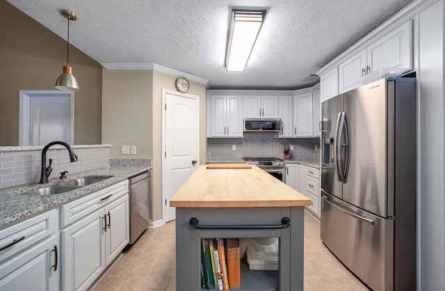 kitchen featuring butcher block countertops, a sink, stainless steel appliances, and light tile patterned floors