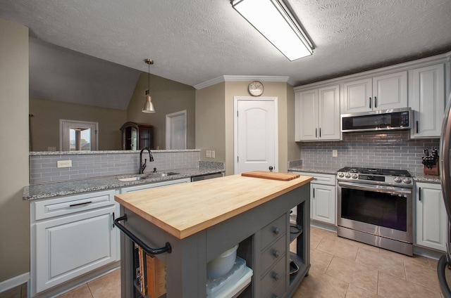 kitchen with a sink, wood counters, appliances with stainless steel finishes, and a kitchen island