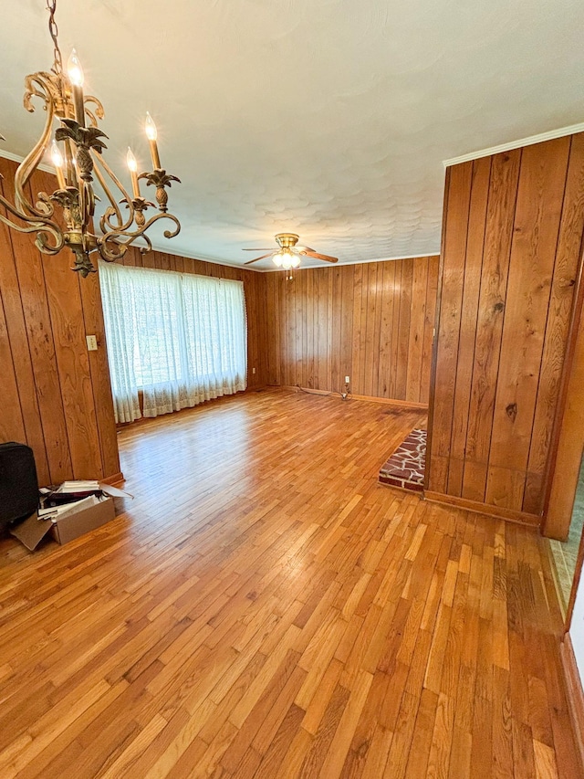126 Zimmerman St, Hohenwald, TN 38462 - unfurnished living room featuring ceiling fan with notable chandelier, wood walls, and light wood-type flooring