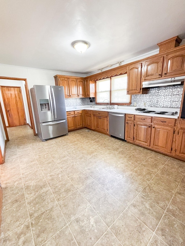 126 Zimmerman St, Hohenwald, TN 38462 - kitchen featuring light countertops, brown cabinets, stainless steel appliances, tasteful backsplash, and under cabinet range hood