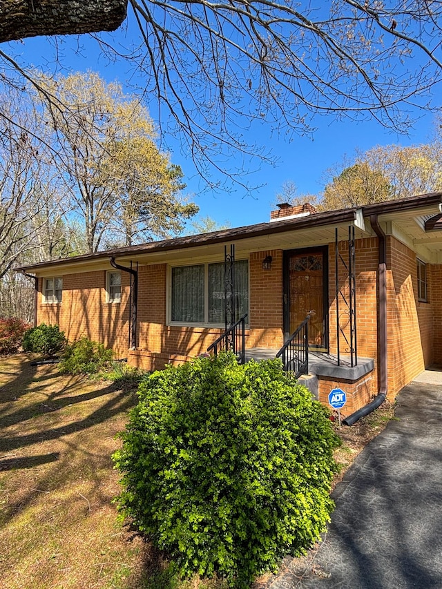 126 Zimmerman St, Hohenwald, TN 38462 - view of front of home featuring a chimney, brick siding, and driveway