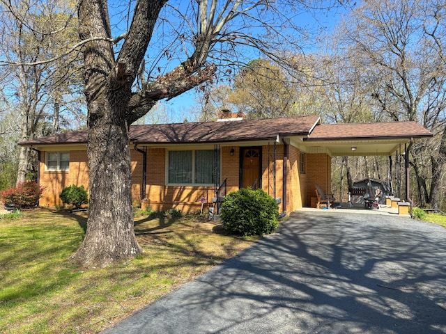 126 Zimmerman St, Hohenwald, TN 38462 - view of front of property featuring driveway, a front yard, brick siding, an attached carport, and a chimney