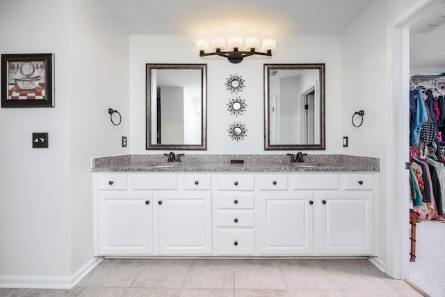 bathroom with double vanity, a sink, tile patterned flooring, and a spacious closet