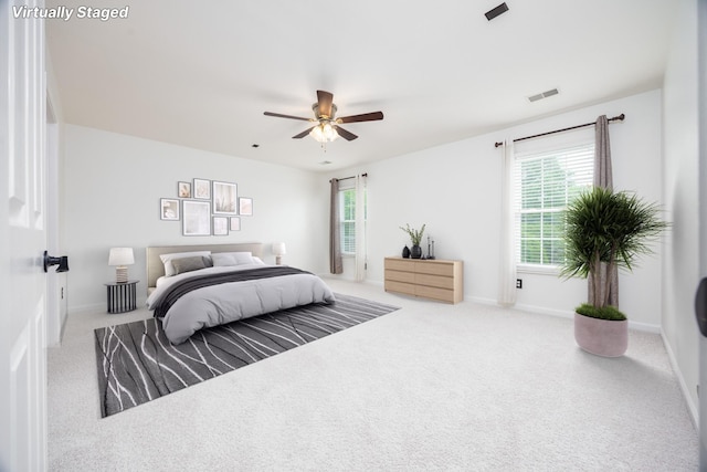carpeted bedroom with baseboards, multiple windows, a ceiling fan, and visible vents