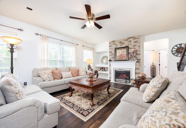 living room with a fireplace, a ceiling fan, dark wood-style flooring, and built in shelves