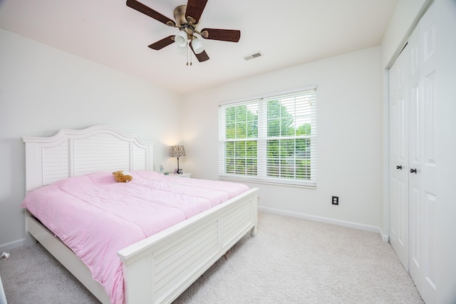 bedroom with baseboards, light carpet, ceiling fan, and a closet