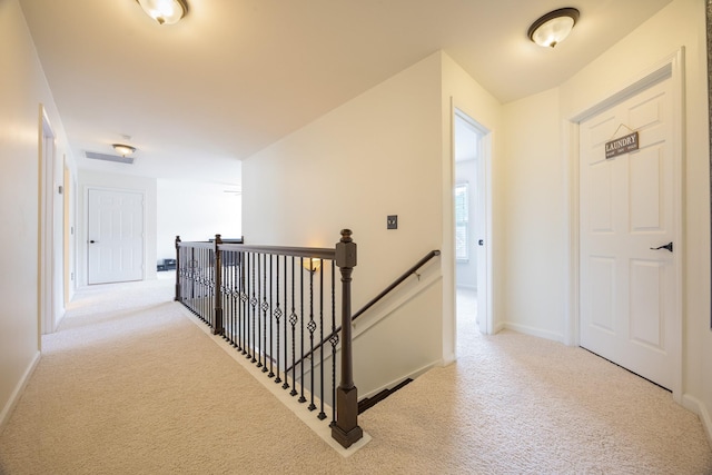 corridor with baseboards, carpet flooring, and an upstairs landing